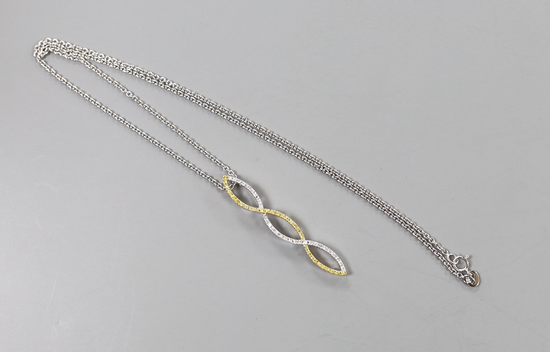 A modern two colour 18ct gold and two colour diamond set overlapping pendant, 42mm, on an 18ct white gold fine link chain, 40cm, 6.9 grams